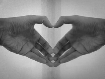 Cropped image of hand reflecting in mirror making heart shape