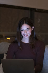 Portrait of young woman using laptop at home