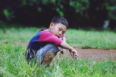 Portrait of a boy squatting.