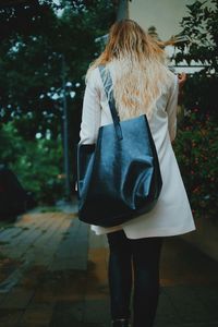 Rear view of woman walking on footpath during rainy season