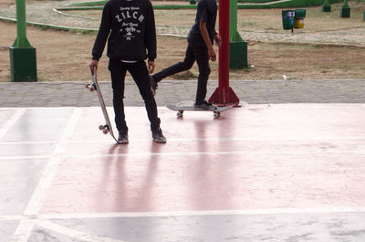 Low section of people skateboarding on footpath