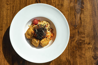 Top view of fusion spaghetti topped with ebiko and seaweed attached with fried breaded meat. 