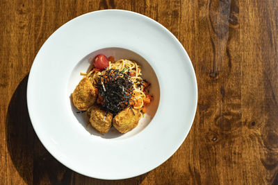 Top view of fusion spaghetti topped with ebiko and seaweed attached with fried breaded meatball.