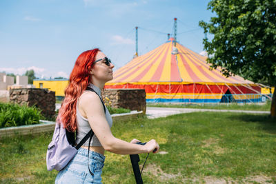 Young bright woman smiles and rides electric scooter in the summer in the city