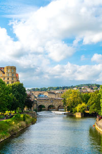 Arch bridge over river amidst buildings against sky