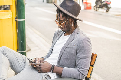 Man holding umbrella while sitting on road