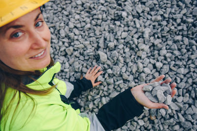 Portrait of smiling female worker holding gravels at construction site