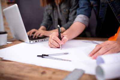 Midsection of woman using mobile phone on table
