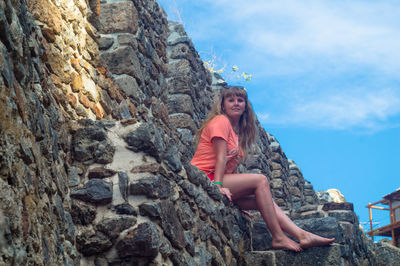 Portrait of woman sitting on against wall