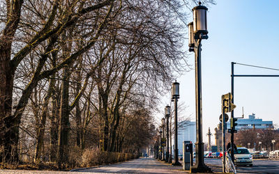 Road amidst bare trees against sky in winter