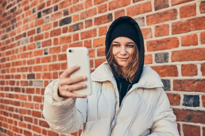 Young woman having video call, talking remotely, taking selfie photo holding smartphone