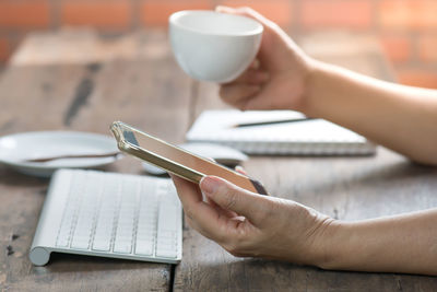 Close-up of woman holding coffee cup on table