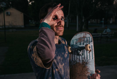 Close-up of man gesturing while holding skateboard