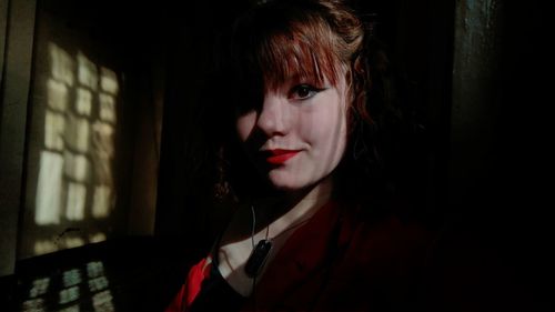 Close-up portrait of beautiful woman standing in darkroom