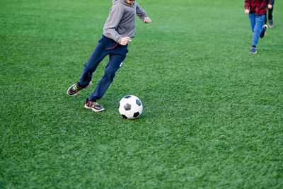 The boy plays football in the yard, on the lawn. child kicks the ball close up