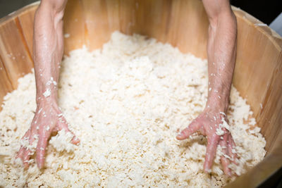 High angle view of worker mixing mozzarella cheese in wooden container at factory