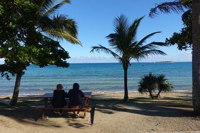 People sitting on beach by sea against sky