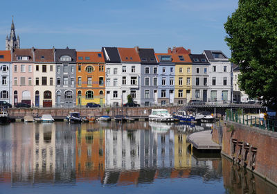 Buildings by canal against sky in city