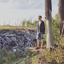 Full length of boy standing by firewood on field