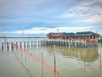 Stilt houses over sea against sky