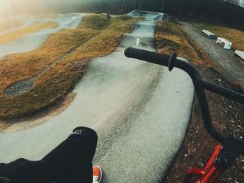 Low section of person with bicycle on road