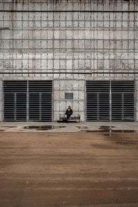 Woman sitting on bench against building