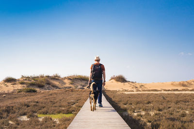 Rear view of man riding motorcycle against clear blue sky