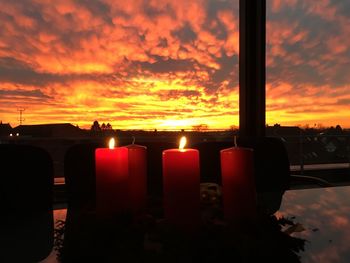 Close-up of illuminated candle against sky during sunset