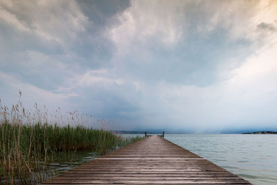 Boardwalk leading towards pier against sky