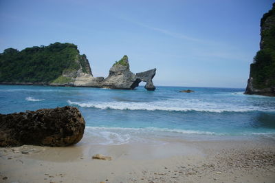 Rock formation on beach against blue sky