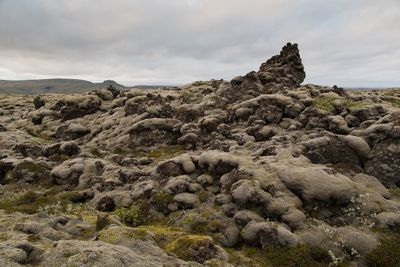 Rock formation by sea against sky