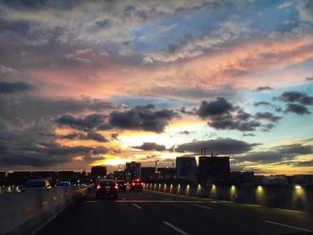 Cars on road against sky during sunset