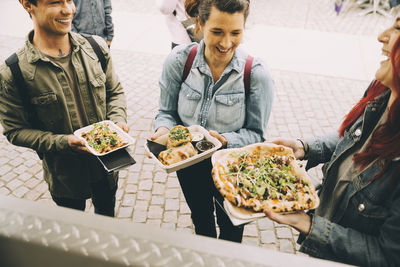 Male and female customers with food plate standing in city