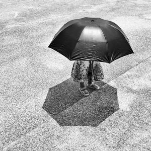 High angle view of woman with umbrella standing on road