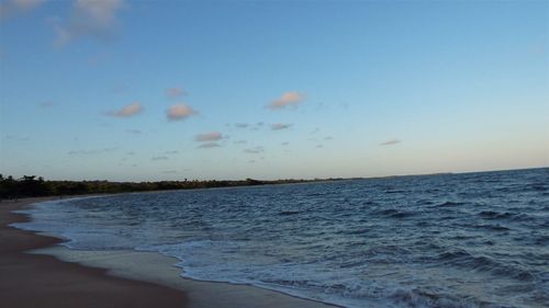 Scenic view of beach against clear sky at sunset