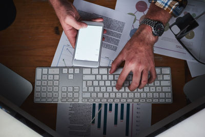 Cropped hands of businessman using laptop on table