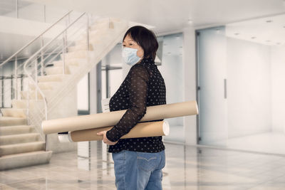 Side view of woman standing against staircase