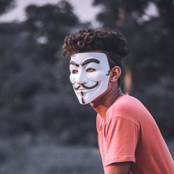 Portrait of young woman wearing mask against blurred background