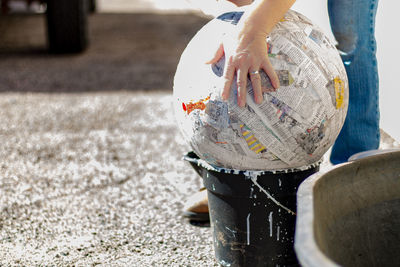 Cropped image of hand touching papier mache ball on bucket