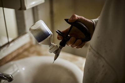 Teenage boy holding syringe above bathroom sink at farm