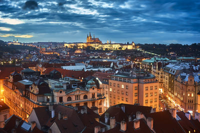 High angle view of illuminated cityscape against cloudy sky at dusk