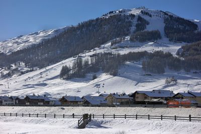 Snow covered houses and mountains against sky