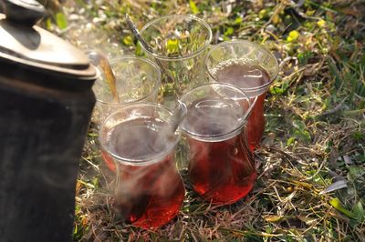 High angle view of teapot pouring turkish tea in cup on field