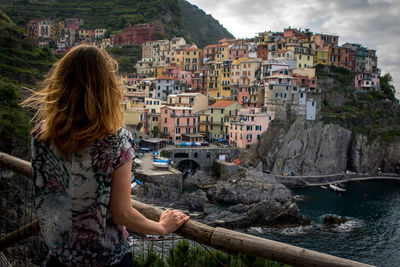 Woman looking at sea by cityscape