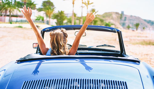 Woman with arms raised in car