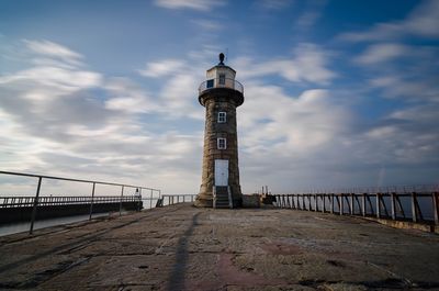 Lighthouse by sea against sky