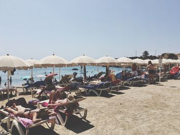 Group of people on beach against clear sky