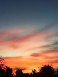 Silhouette trees against dramatic sky during sunset