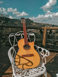 Close-up of guitar on railing against sky