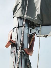 Low angle view of person holding rope against sky